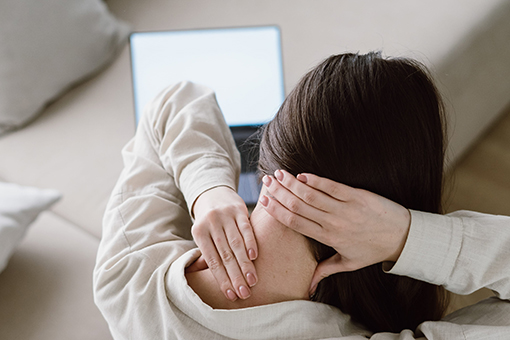 Woman with Neck Injury Searching For Whiplash Treatment Clinic in Brandon FL Using Laptop
